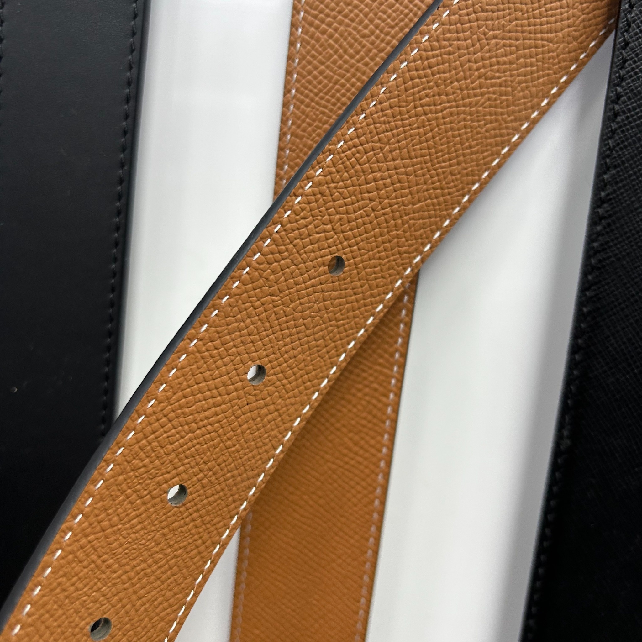 Tan textured leather belt adjustment holes detail