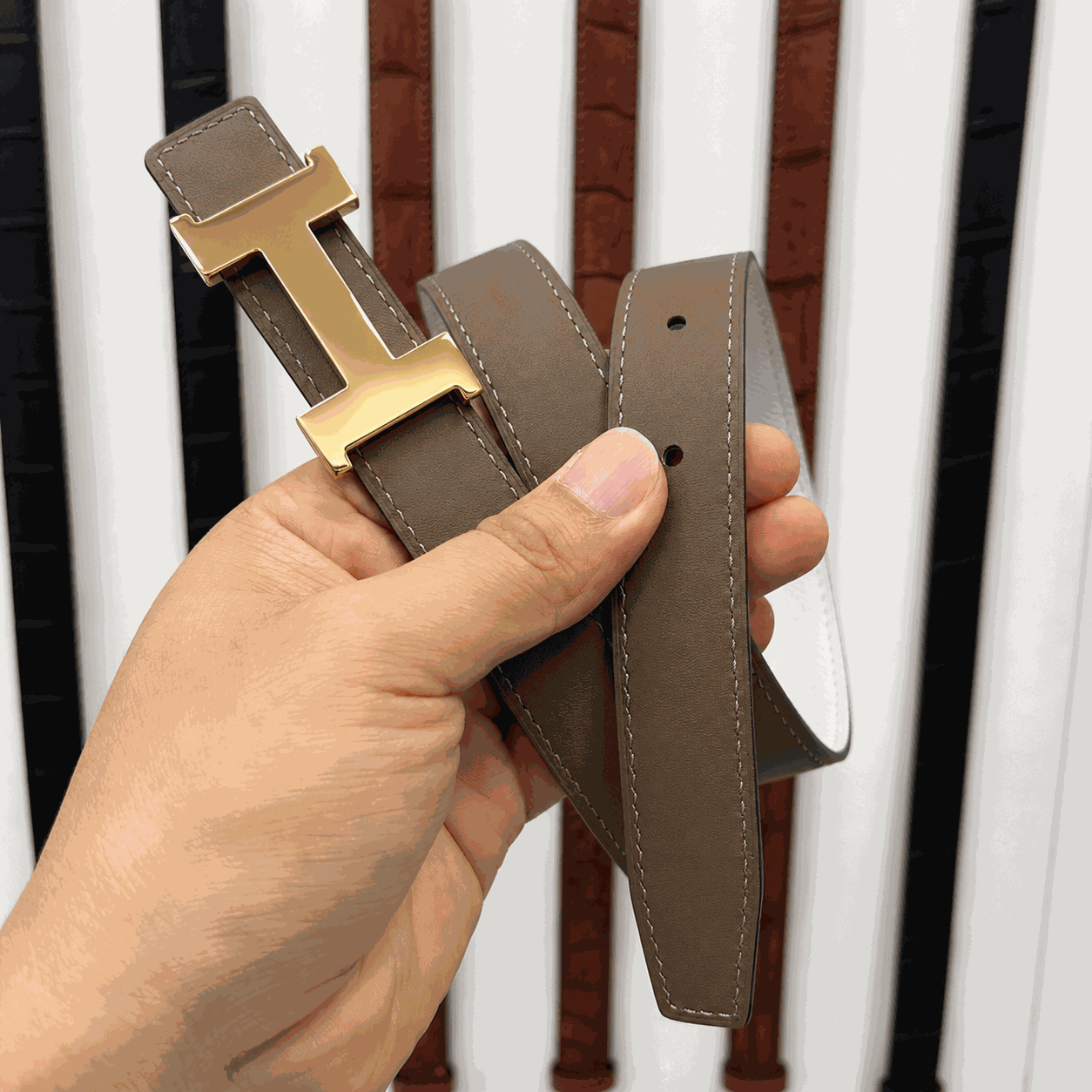 Handheld taupe leather belt with gold H-style buckle