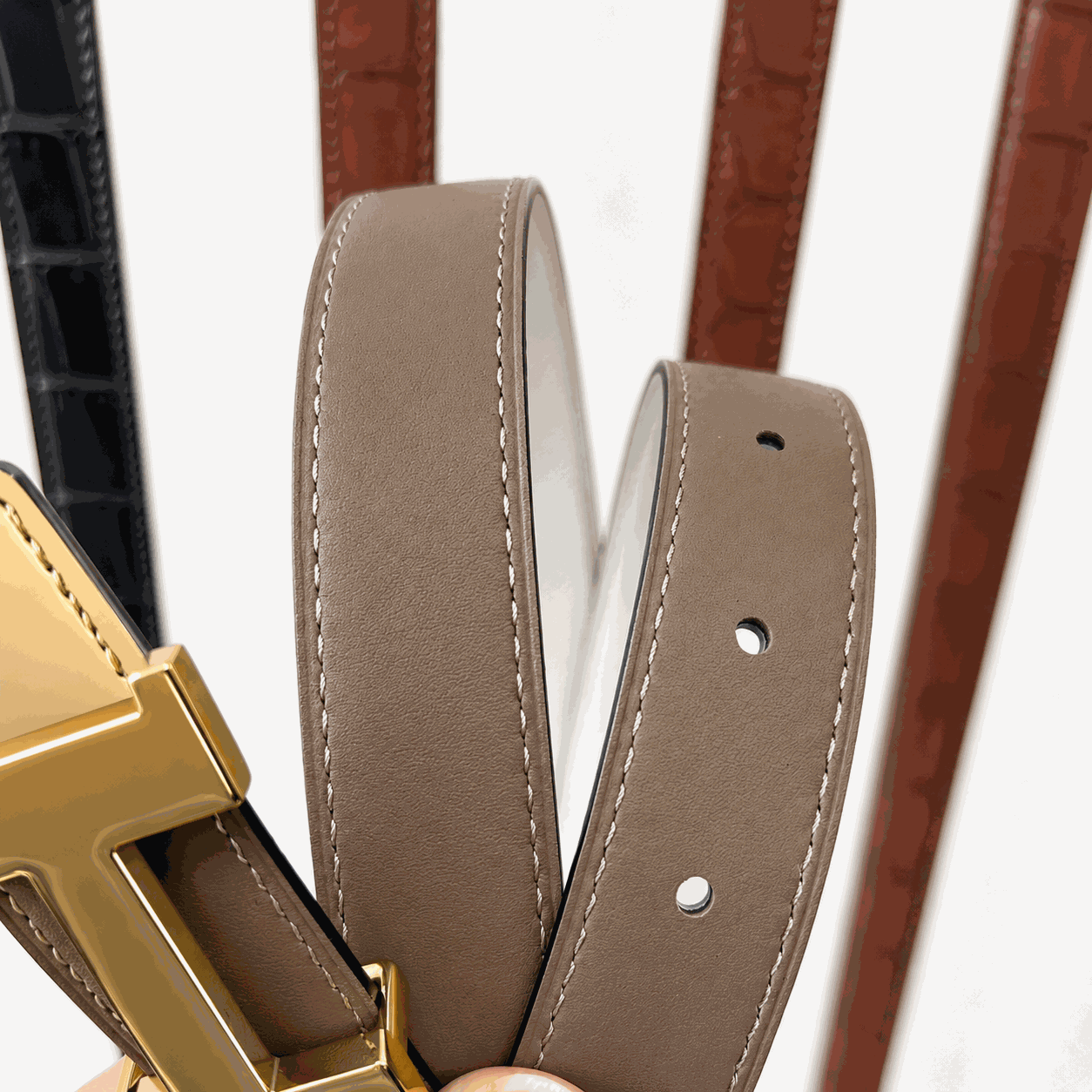 Taupe leather belt strap stitching and adjustment holes detail